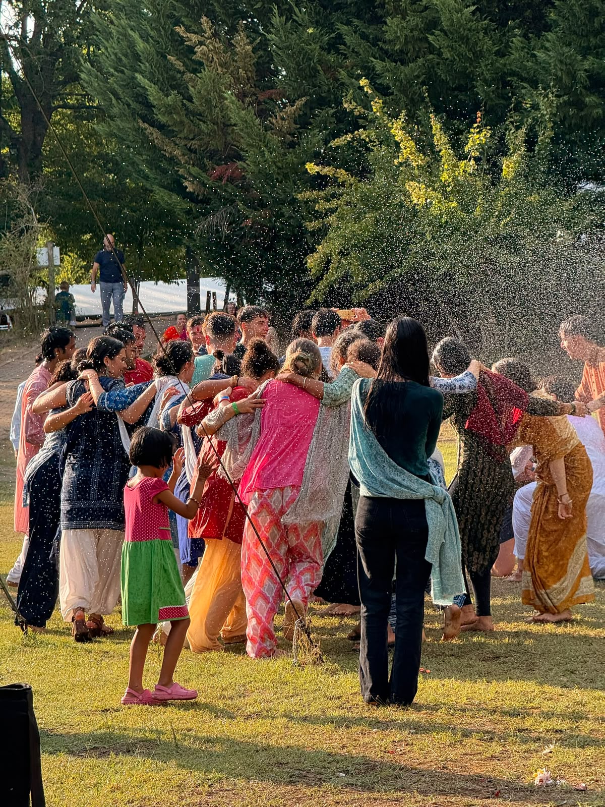 The collective embracing in a circle under a spray of water