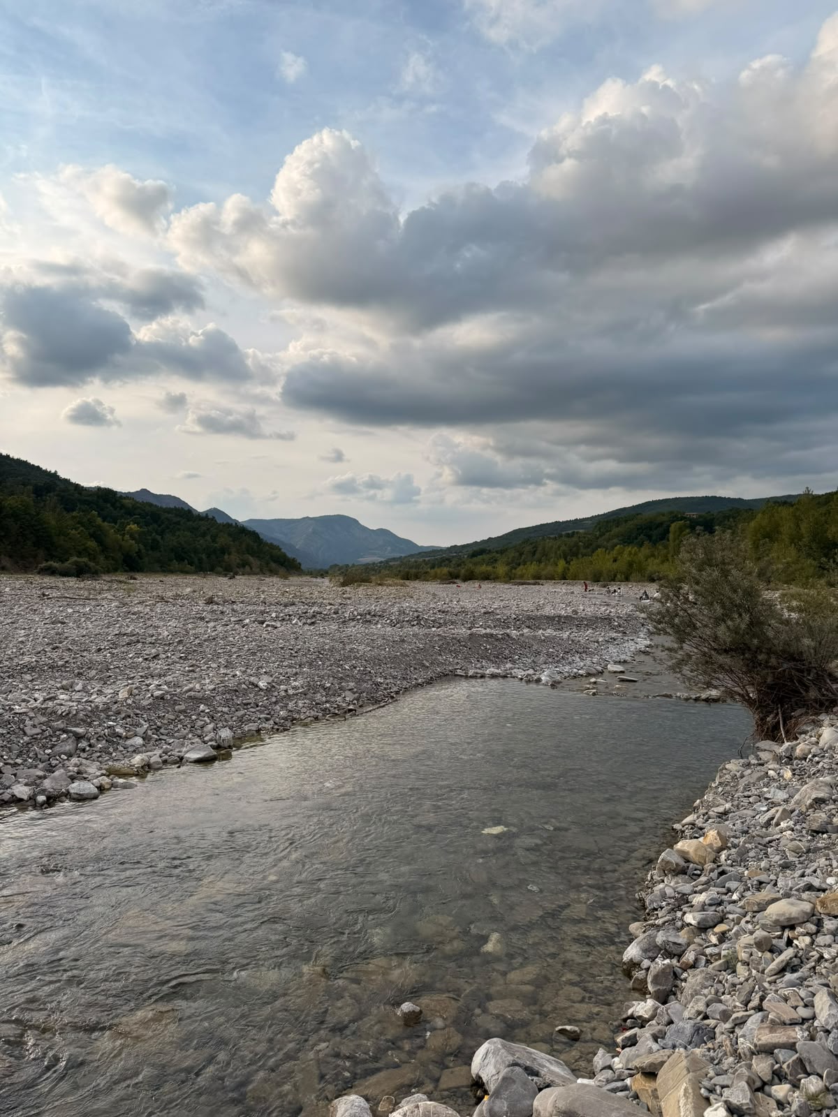 The Borbera river running through stones under a wide sky